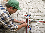 a handyman patches a leaky pipe